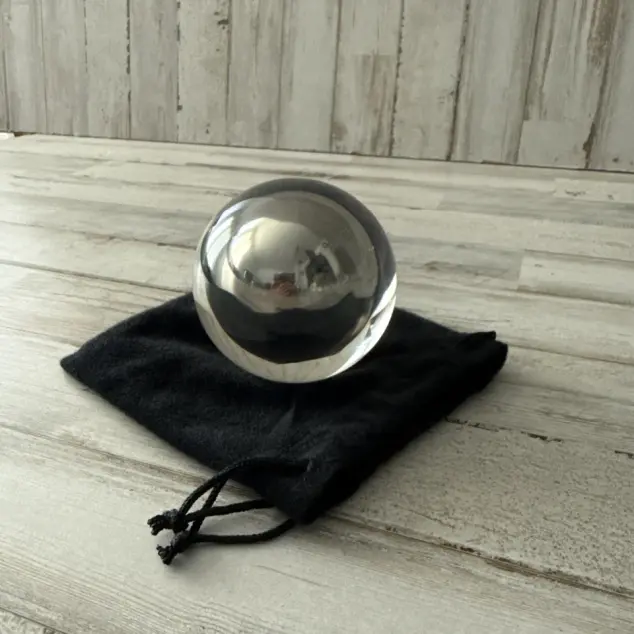 random ebay listing photo of a Fushigi Magic Gravity Ball sitting on top of its black velvet storage bag. The background surface and wall is light gray wood slats.