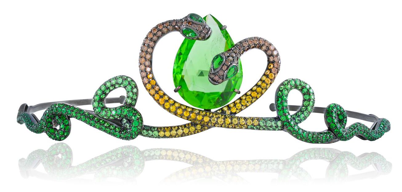 Tiara with 2 snakes on either side and a large green triangular peridot in the middle. The snakes are covered in brown diamonds, yellow sapphires and tsavorite garnets. Their bodies are sinuous and the heads meet on either side of the top of the peridot.
