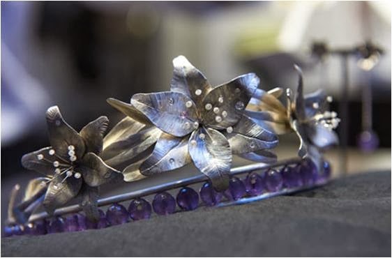 Silver tiara with a base of 25 round amethysts. On top are 3 silver lillies with the center one being slightly larger. Each lily has stamens that are topped with small diamonds.