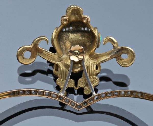 Photo of the back side of the tiara, showing how the figure's head is connected to the band of the tiara. There is a fastening on the head, which allows it to be removed and worn as a brooch.