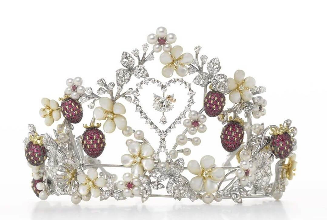 Tiara made of white gold, diamonds, pearls and rubies. It features floral and leaf elements, 7 strawberries studded with rubies, an open diamond heart in the center and a diamond Hello Kitty dangling from the center of the heart.
