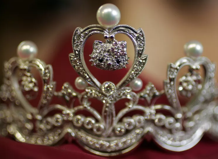 Close up image of the central section of the platinum Hello Kitty tiara showing the detail on the face. The eyes are black diamonds and pink diamonds on the right ear make a bow. 