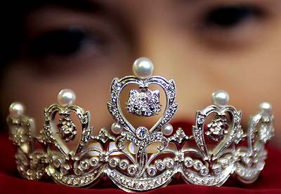 Small platinum Hello Kitty tiara. Heart-shaped frames are topped with round pearls. From the center of each heart dangles a Hello Kitty face charm. There are 2 rows of diamond swags at the bottom. 