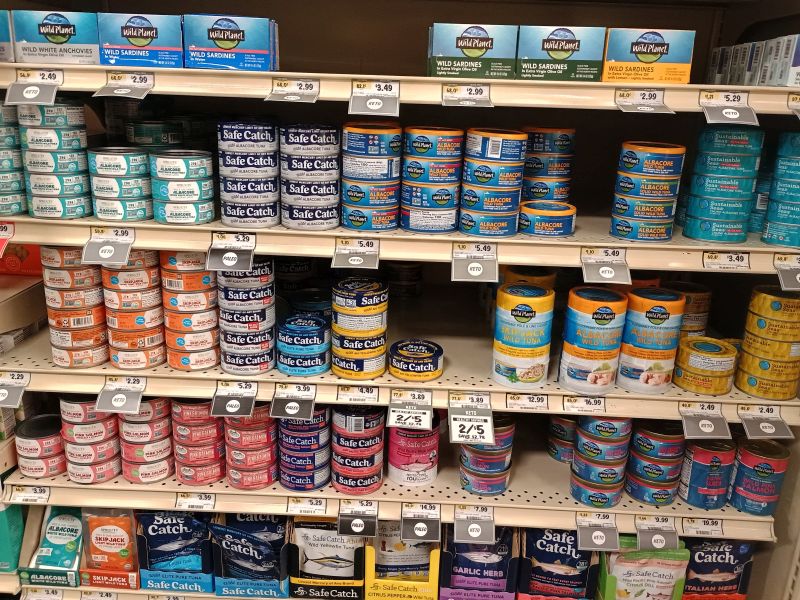 tuna aisle at the natural foods market, showing numerous cans of tuna, sardines and mackeral on the shelves